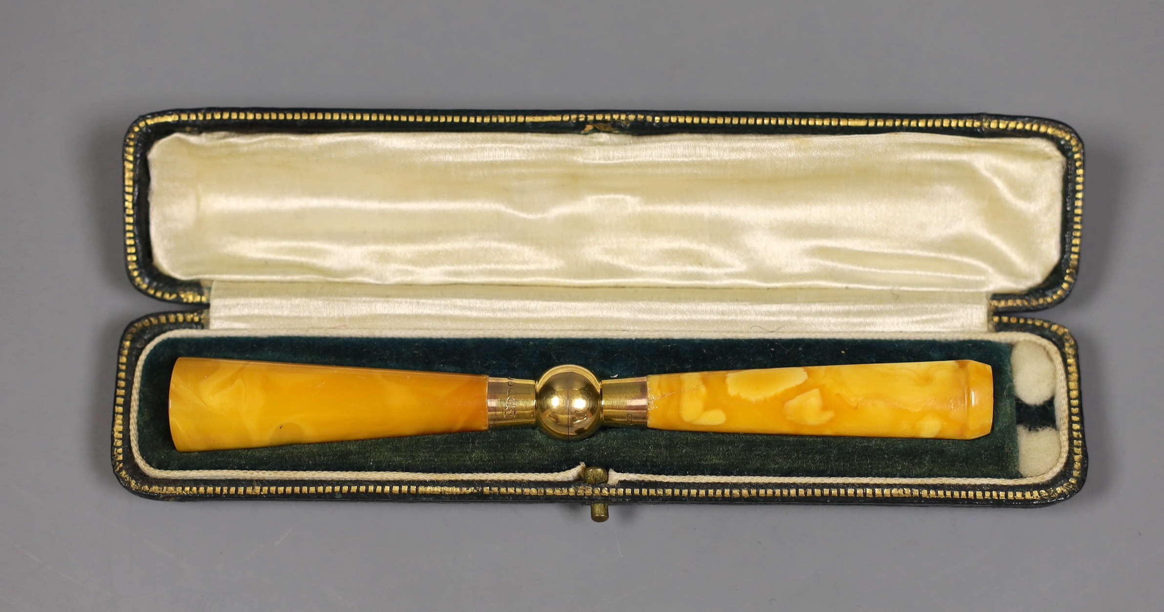 A cased Art Deco 9ct mounted amber cigarette holder